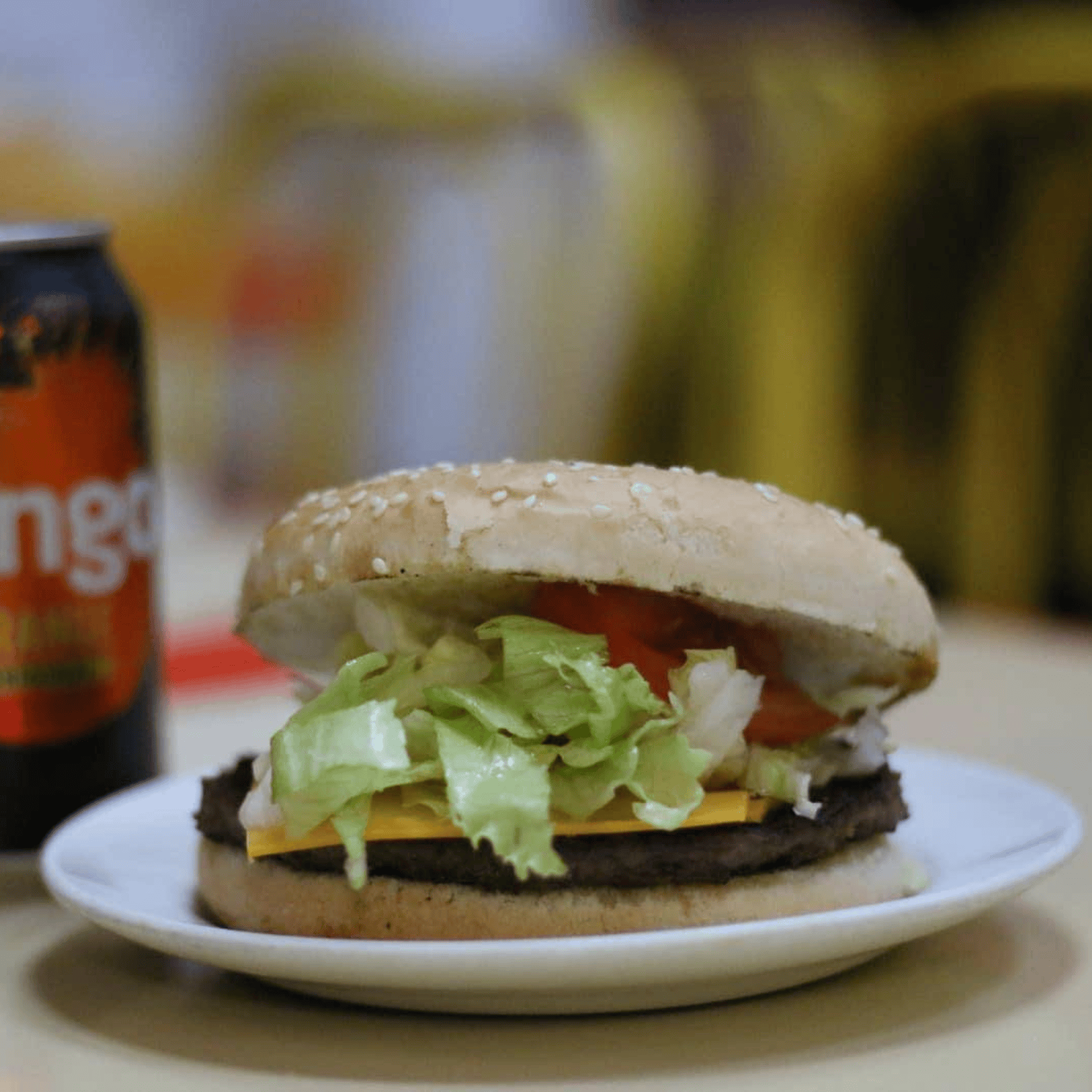 Get Stuffed’s sesame seed bun cheeseburger with lettuce and tomato, and a soft drink can 
                      nearby.
